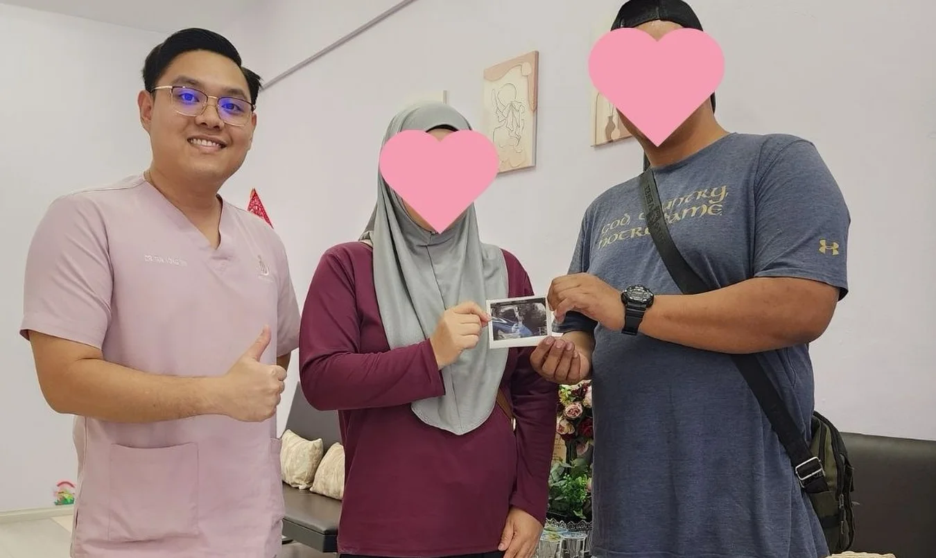 Dr. Tan with a couple holding their first ultrasound scan picture at Heracare Clinic, the couple's faces covered for privacy